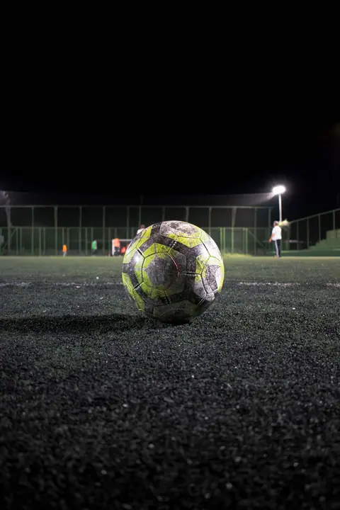 Match ball resting on an artificial turf pitch under lights